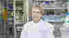 An image of a smiling Professor Ros Eeles, looking directly at the camera, wearing an ICR labcoat in a lab